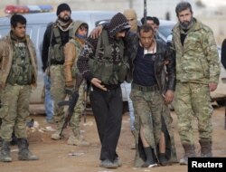 FILE - Free Syrian Army fighters help a fellow fighter, who was injured during fighting near Qabasin town, northern Syria, Jan. 12, 2017.