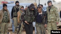 FILE - Free Syrian Army fighters help a fellow fighter, who was injured during fighting near Qabasin town, northern Syria, Jan. 12, 2017.