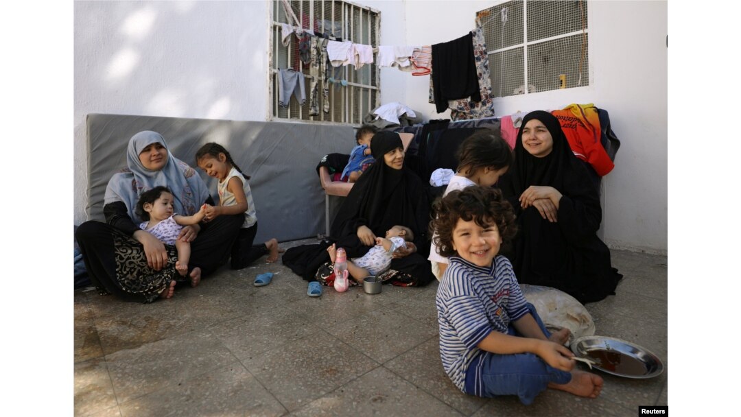 FILE - From left, Tunisians Khadouja al-Humri, Iman Othman and Lebanese Nour al-Huda, wives of former Islamic State fighters, sit with their children at a camp for displaced people in Ain Issa, north of Raqqa, Syria, June 21, 2017.