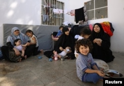 FILE - From left, Tunisians Khadouja al-Humri, Iman Othman and Lebanese Nour al-Huda, wives of former Islamic State fighters, sit with their children at a camp for displaced people in Ain Issa, north of Raqqa, Syria, June 21, 2017.