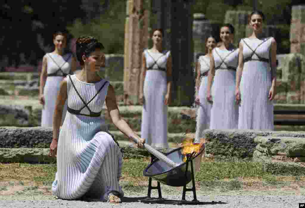 A dancer dressed as a priestess lights the Olympic flame with a parabolic mirror during the ceremonial lighting of the Olympic flame in Ancient Olympia, Greece.