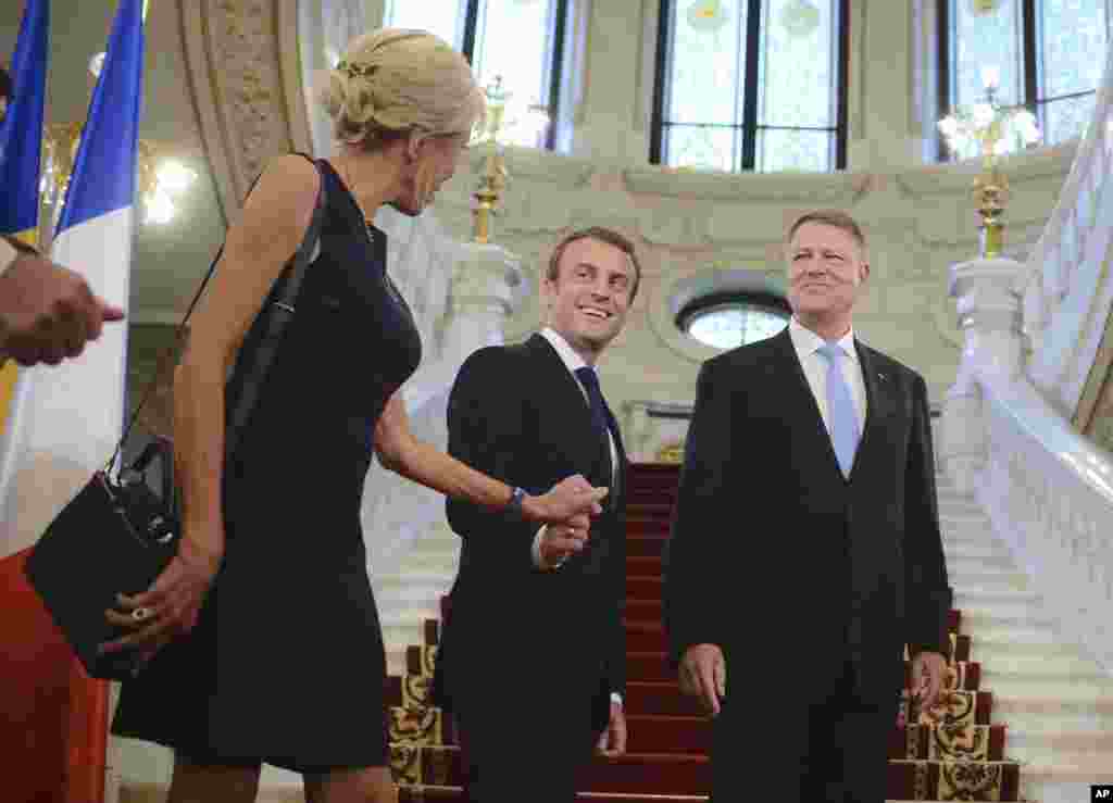 French President Emmanuel Macron,center, holds his wife Brigitte&#39;s hand, as Romanian counterpart Klaus Iohannis smiles, in Bucharest, Romania.