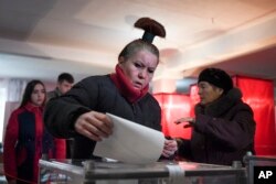   A woman drops her ballot in a polling station during elections by rebels in Donetsk (Ukraine), November 11, 2018. 