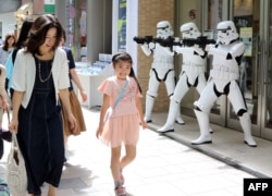 Pedestrians pass before Storm Troopers at a toy shop in Tokyo. May 4th is called the "Star Wars Day" among Star Wars fans as the famous phrase "May the Force be with you" in the movie sounds like "May the 4th be with you," May 4, 2015.