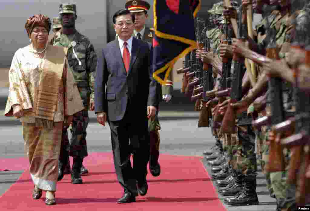 Le président Hu Jintao de la Chine (c) et son homologue du Liberia, Ellen Johnson-Sirleaf (g) passent les troupes en revue à Monrovia, 1er février 2007.&nbsp;