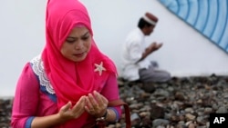 A woman mourns victims of the December 2004 Asian tsunami, praying at a mass grave in Siron, Aceh Besar, Indonesia, Dec. 26, 2014. 