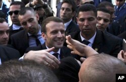 FILE - French President Emmanuel Macron shakes hands as he meets residents in Algiers, Algeria, Dec.6, 2017.