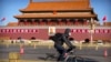 2020年2月4日星期二，一名男子骑着自行车穿过北京天安门广场时，戴着口罩。
