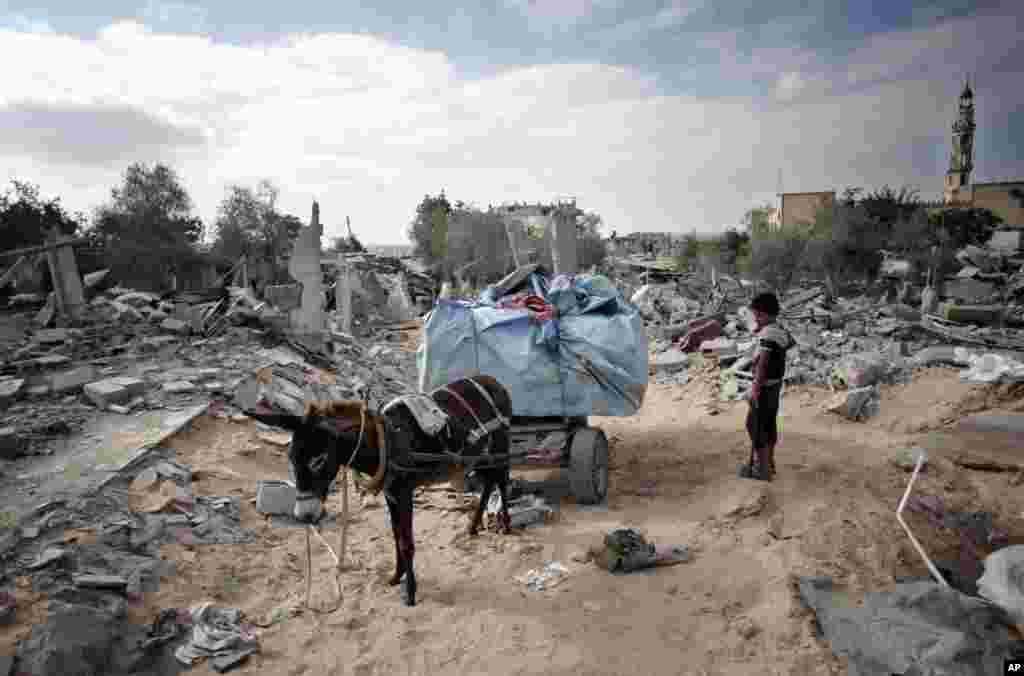 A Palestinian boy stands next to a donkey cart loaded with salvaged belongings from his family's destroyed house in the town of Beit Lahiya, northern Gaza Strip, Monday, Aug. 11, 2014.