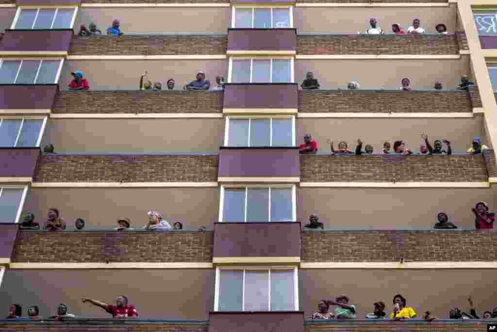 People living in the Hillbrow neighborhood of downtown Johannesburg, confined in an attempt to prevent the spread coronavirus, stand and wave from their balconies.