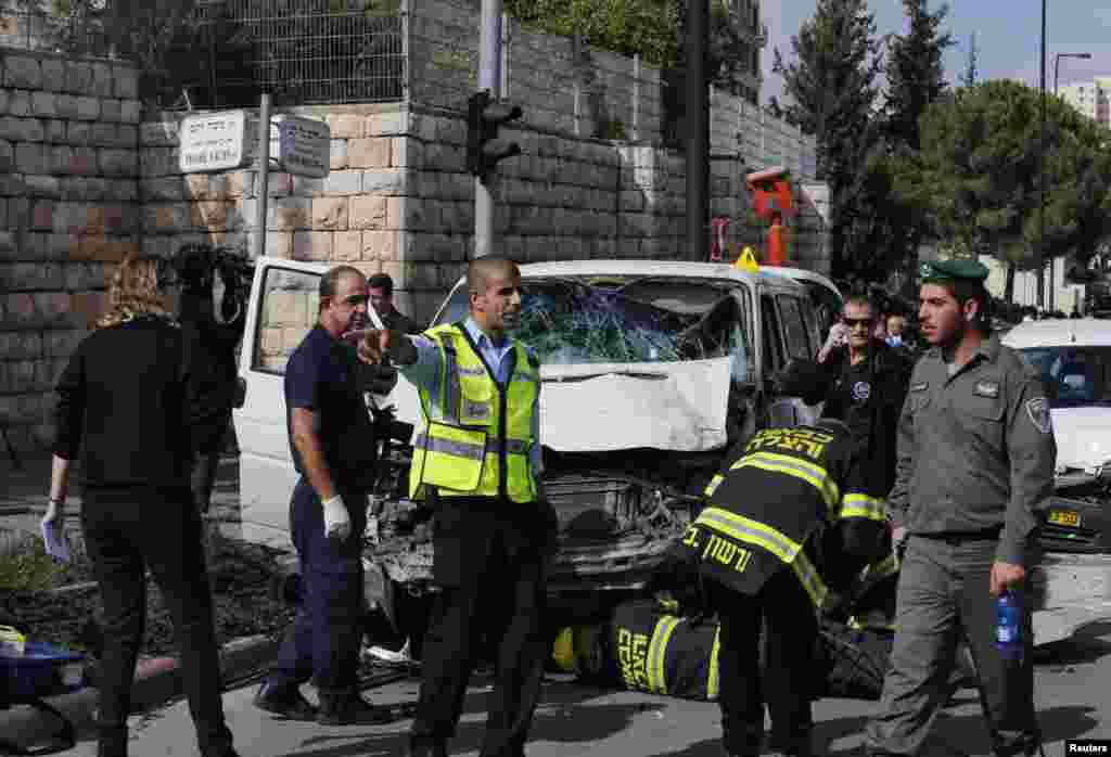 An Israeli police officer gestures in front of the vehicle of a Palestinian motorist who rammed into pedestrians at the scene of the attack in Jerusalem, Nov. 5, 2014. 