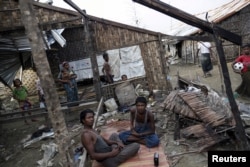FILE - Rohingya people pass their time in a damaged shelter in Rohingya IDP camp outside Sittwe, Rakhine state, Myanmar.