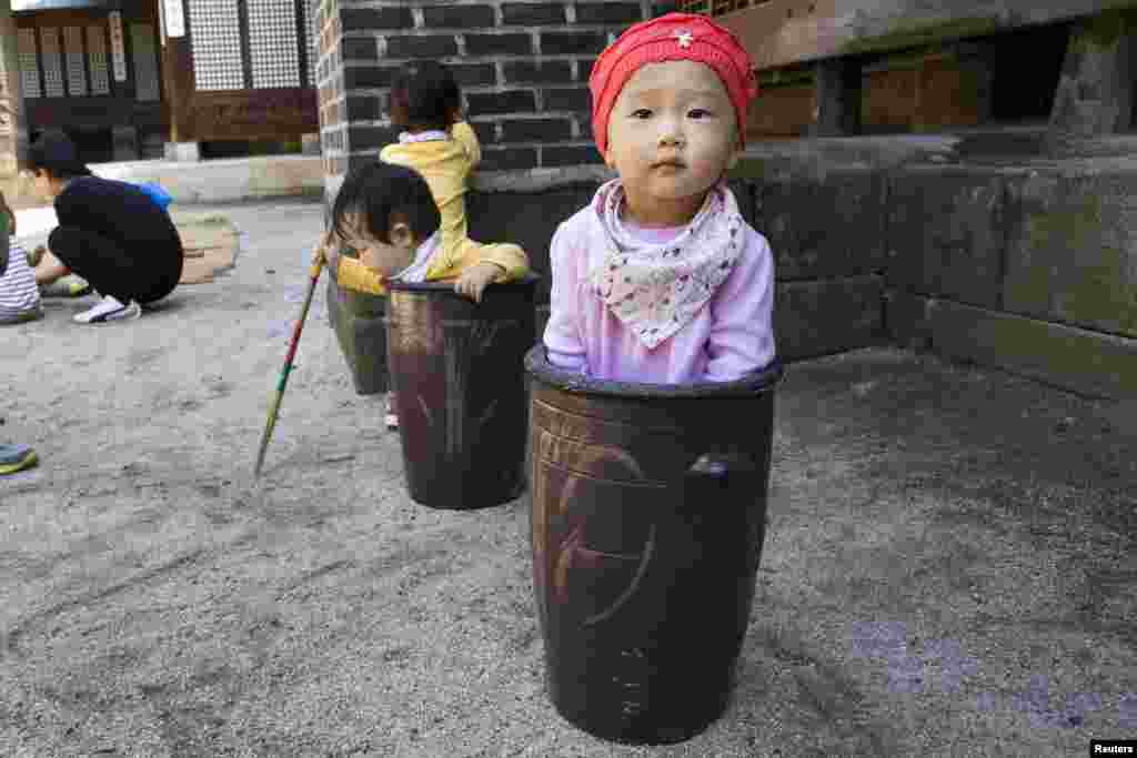 Bé Jung Ha-yoon, 2 tuổi, ngồi chơi trong một bình gốm cùng những em nhỏ khác trong Lễ hội ẩm thực truyền thống của giới quý tộc và hoàng gia, tổ chức tại Cung điện Unhyeon, hay Cung điện Unhyeongung, tại Seoul, Hàn Quốc.