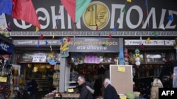 People walk past a 'one euro' store in central Athens, Greece, Feb. 28, 2017. Greece and its creditors have reached a deal that will restart bailout loan payments and keep the country from facing default and reigniting a eurozone crisis this summer, officials said Tuesday.