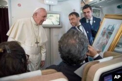 Pope Francis receives a gift from a journalist during his flight from Abu Dhabi to Rome, Tuesday, Feb. 5, 2019. Pope Francis has concluded his historic visit to the Arabian Peninsula with the first-ever papal Mass in the birthplace of Islam.