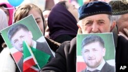 FILE - People hold portraits of Chechen leader Ramzan Kadyrov as they take part in a rally marking the 13th anniversary of the adoption of the Constitution of Russian region of Chechnya, in the regional capital of Grozny, March 23, 2016.
