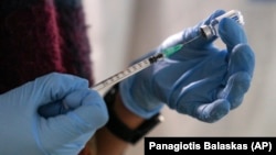 An employee from the National Health Organization (EODY) prepares a Johnson and Johnson vaccine against COVID-19 at Karatepe refugee camp, on the northeastern Aegean island of Lesbos, Greece, on December 15, 2021. (AP Photo/Panagiotis Balaskas, File)