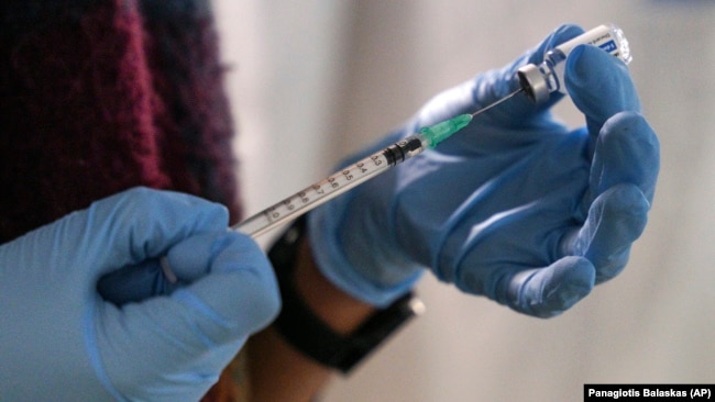 An employee from the National Health Organization (EODY) prepares a Johnson and Johnson vaccine against COVID-19 at Karatepe refugee camp, on the northeastern Aegean island of Lesbos, Greece, on December 15, 2021. (AP Photo/Panagiotis Balaskas, File)