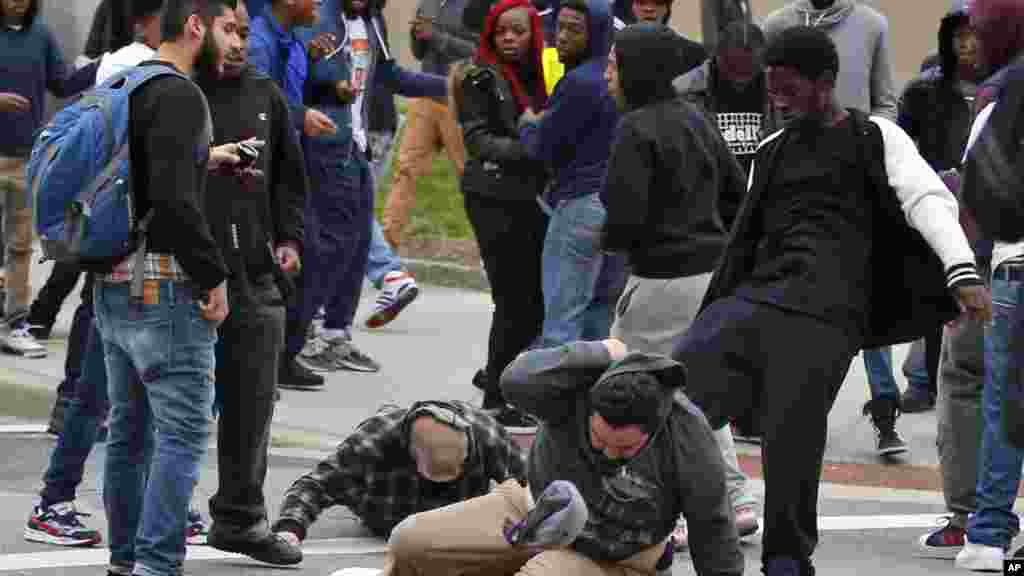 A man is kicked as he attempts to get up after being knocked down, following a march to City Hall for Freddie Gray, in Baltimore, April 25, 2015.