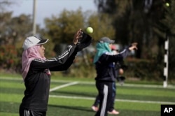 Palestinian women practice with tennis balls while training for an all-women's baseball game on a soccer field in Khan Younis, southern Gaza Strip, March 19, 2017.