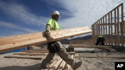 Construction worker Miguel Fonseca carries lumber as he works on a house frame for a new home, Chula Vista, Calif., Nov. 16, 2012.