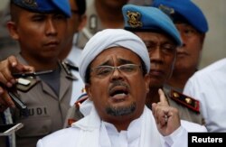 FILE - Habib Rizieq gestures while speaking to the media upon his arrival at Jakarta Police headquarters in Jakarta, Indonesia, Feb. 1, 2017.