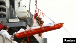 馬耳他武裝部隊海員看他們找到的一具遇難者遺體從艦艇上下放到港口