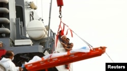 马耳他武装部队海员看他们找到的一具遇难者遗体从舰艇上下放到港口。