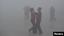 FILE - People wearing masks dance at a square in heavy smog during a polluted day in Fuyang, Anhui province, China, Jan. 3, 2017. 