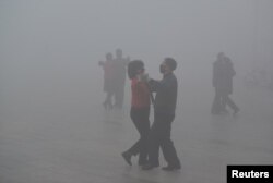 FILE - People wearing masks dance at a square in heavy smog during a polluted day in Fuyang, Anhui province, China, Jan. 3, 2017.