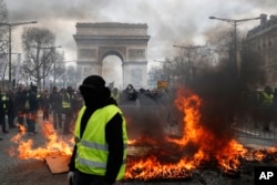 A yellow vest protester walks past a fire on Champs Elysees avenue in Paris, France, March 16, 2019.