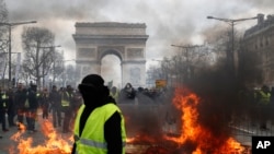A yellow vest protester walks past a fire on Champs Elysees avenue in Paris, France, March 16, 2019.
