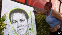 Une femme accroche un panneau en hommage à Mohamed Ali dans le quartier new-yorkais de Brooklyn, le 4 juin 2016. 