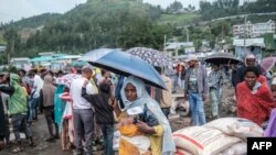 Une femme se tient avec un parapluie à côté de sacs de riz lors d'une distribution de nourriture pour les personnes déplacées à l'intérieur (PDI) de la région d'Amhara, dans la ville de Dessie, en Éthiopie, 