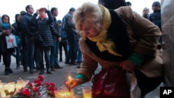 A woman lights a candle at an entrance of Sennaya subway station after an explosion on the subway in St.Petersburg, Russia, Monday, April 3, 2017.