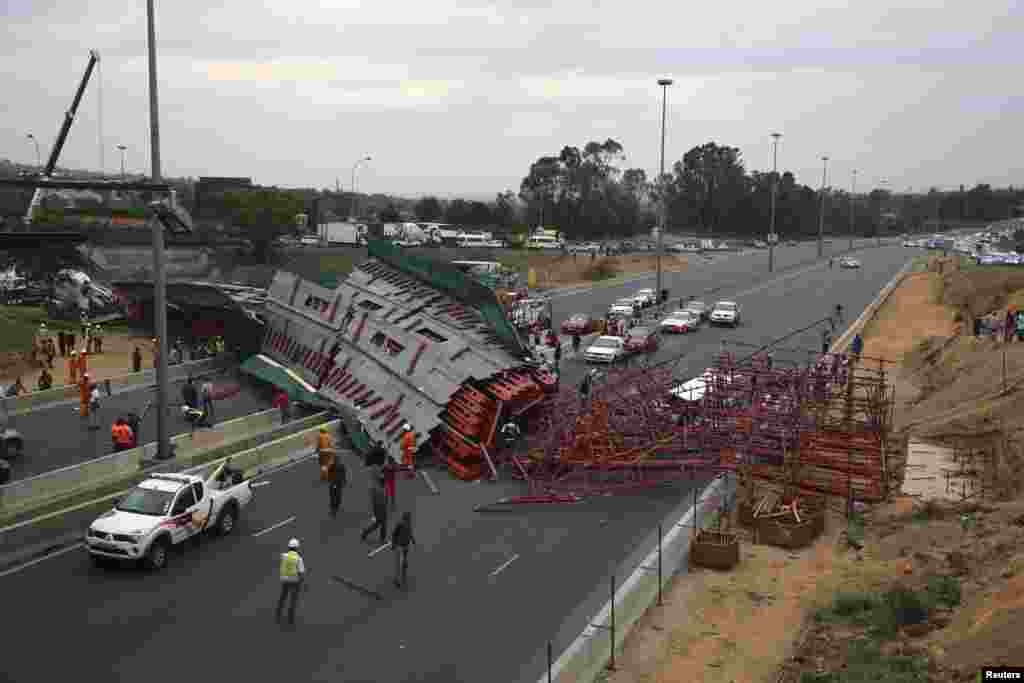 Warga mengamati setelah perancah atau scaffolding sebuah jembatan yang sedang dibangun ambruk di jalan tol M1 menuju Sandton, Afrika Selatan. Kecelakaan itu menewaskan dua orang, sementara 20 lainnya cedera, menurut kantor SAR lokal.