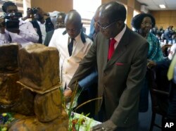 Zimbabwe's President Robert Mugabe cuts his birthday cake as he marks his 93rd birthday at his offices in Harare, Tuesday, Feb. 21, 2017. Mugabe described his wife Grace, an increasingly political figure, as "fireworks" in an interview marking his 93rd bi