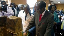 Zimbabwe's President Robert Mugabe cuts his birthday cake as he marks his 93rd birthday at his offices in Harare, Tuesday, Feb. 21, 2017. Mugabe described his wife Grace, an increasingly political figure, as "fireworks" in an interview marking his 93rd birthday.