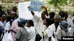 FILE - Zimbabwean riot policemen stand in front of doctors and nurses who are demonstrating over the deteriorating health system, outside Parirenyatwa group of hospitals in Harare, Nov. 18, 2008.