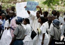 FILE - Zimbabwean riot policemen stand in front of doctors and nurses who are demonstrating over the deteriorating health system, outside Parirenyatwa group of hospitals in Harare.