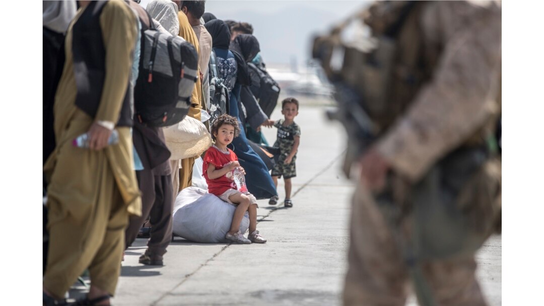 Seorang anak menunggu bersama keluarganya untuk naik Boeing C-17 Globemaster III Angkatan Udara AS selama evakuasi di Bandara Internasional Hamid Karzai di Kabul. (Foto: AP)