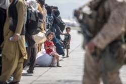 Seorang anak menunggu bersama keluarganya untuk naik Boeing C-17 Globemaster III Angkatan Udara AS selama evakuasi di Bandara Internasional Hamid Karzai di Kabul. (Foto: AP)