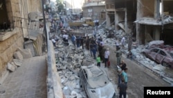 People inspect the damage at a site after it was hit by shelling carried out by rebels at Syrian government-held areas of Aleppo, Syria, in this handout picture provided by SANA, July 11, 2016.