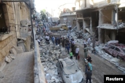 People inspect the damage at a site after it was hit by shelling carried out by rebels at Syrian government-held areas of Aleppo, Syria, in this handout picture provided by SANA, July 11, 2016.