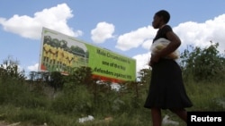 A Zimbabean woman walks past a billboard promoting male cirumcision to combat AIDS in the capital (Philimon Bulawayo/Reuters)