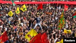 Demonstrators hold Kurdish flags and flags with portraits of the jailed Kurdistan Workers Party [PKK] leader Abdullah Ocalan during a gathering to celebrate Newroz in the southeastern Turkish city of Diyarbakir, March 21, 2013.