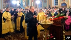 Russian President Vladimir Putin, center, attends midnight Orthodox Christmas Mass in a church in the village of Turginovo, about 150 kilometers (90 miles) northwest of Turginovo, Russia, late Wednesday, Jan. 6, 2016.