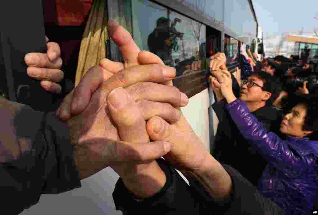 Des Sud-Coréens tiennent les mains de leur parent Corée du Nord sur un bus après l&#39;assemblée Réunion de famille Séparés à Diamond Mountain en Corée du Nord, le 25 février 2014.