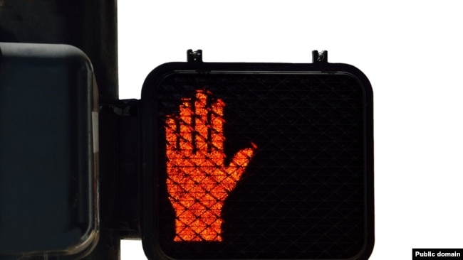 A pedestrian light displays the red symbol for "Don't walk."