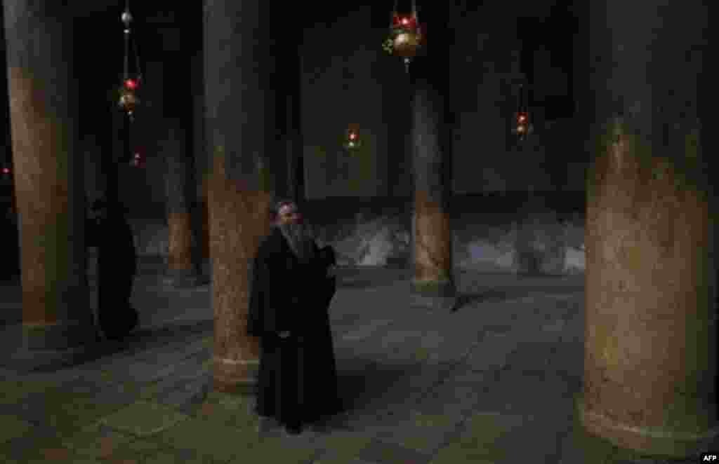 A Christian Orthodox priest stands during a mass in the Church of the Nativity, traditionally believed by Christians to be the birthplace of Jesus Christ, during the Orthodox Christmas in the West Bank city of Bethlehem, Friday, Jan. 6, 2012. (AP Photo/Du